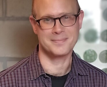 A person with glasses and a plaid shirt