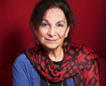Portrait of a person with dark hair, wearing a blue top and a red patterned scarf.
