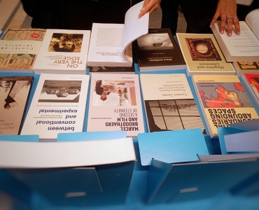 Leuven University Press books on display at a conference book exhibition, with a visitor browsing the titles.